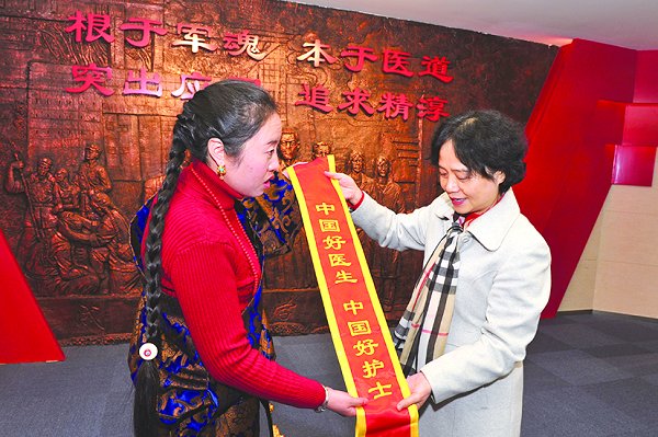 “白求恩奖章”和“中国好医生”　　获得者、2001级毕业生谭晓琴（左）　　向学校捐赠自己的荣誉绶带，校党　　委书记余小平（右）接受赠送。